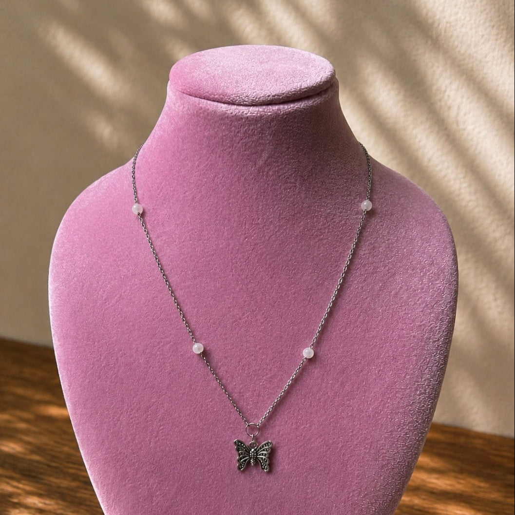 Necklace with a butterfly pendant on a pink velvet mannequin against a neutral background