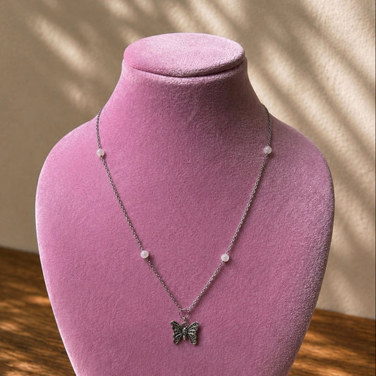 Necklace with a butterfly pendant on a pink velvet mannequin against a neutral background