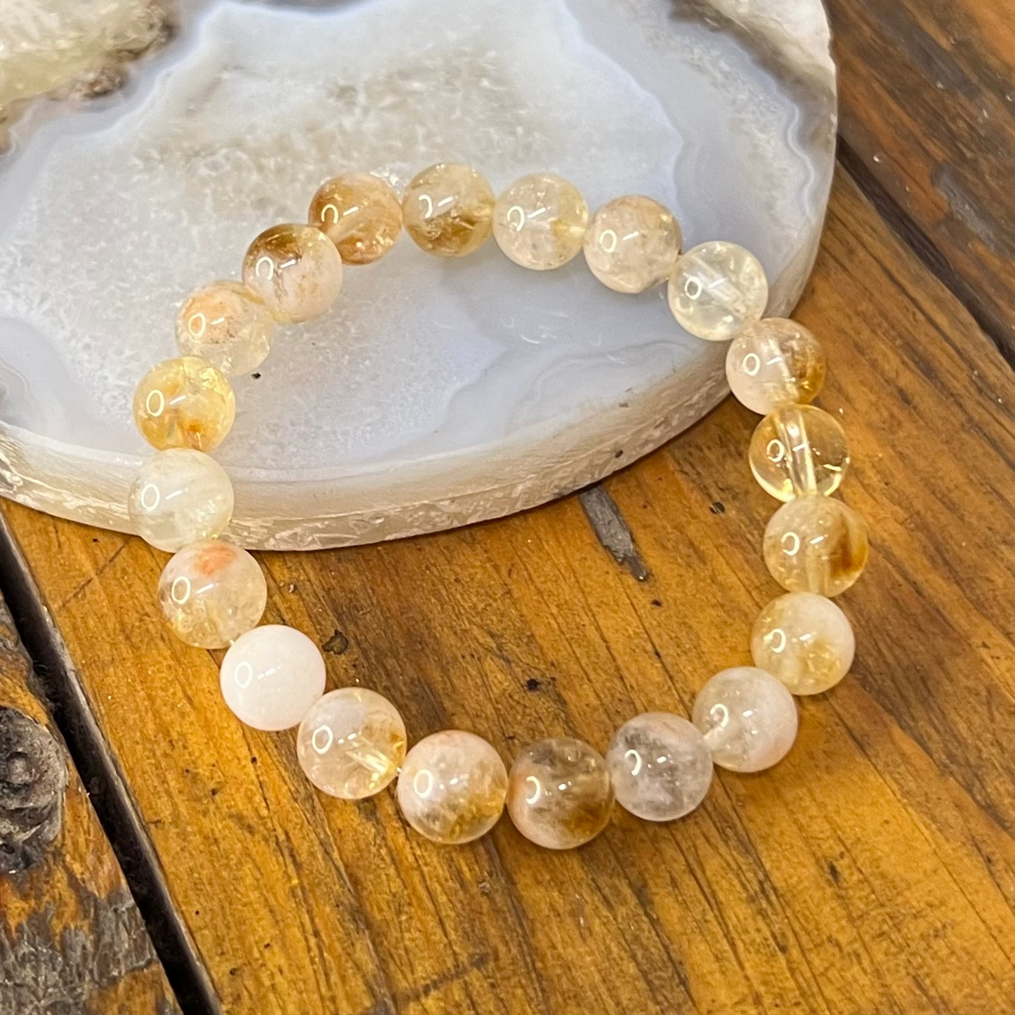 Beaded bracelet on a wooden surface with a decorative stone in the background