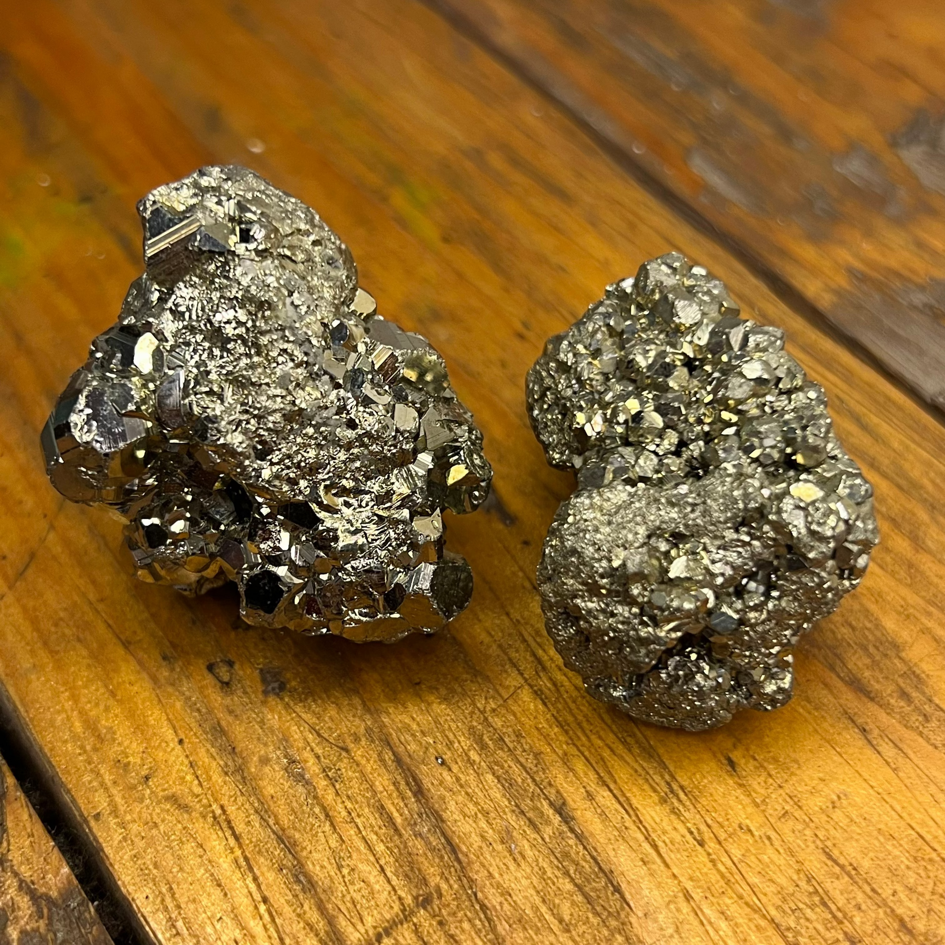 Two metallic mineral specimens on a wooden surface
