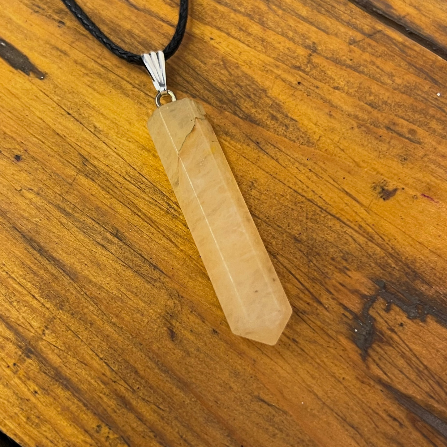 Necklace with a beige crystal pendant on a wooden surface