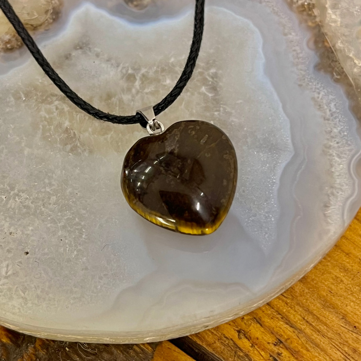 Heart-shaped pendant on a black cord with a natural stone background